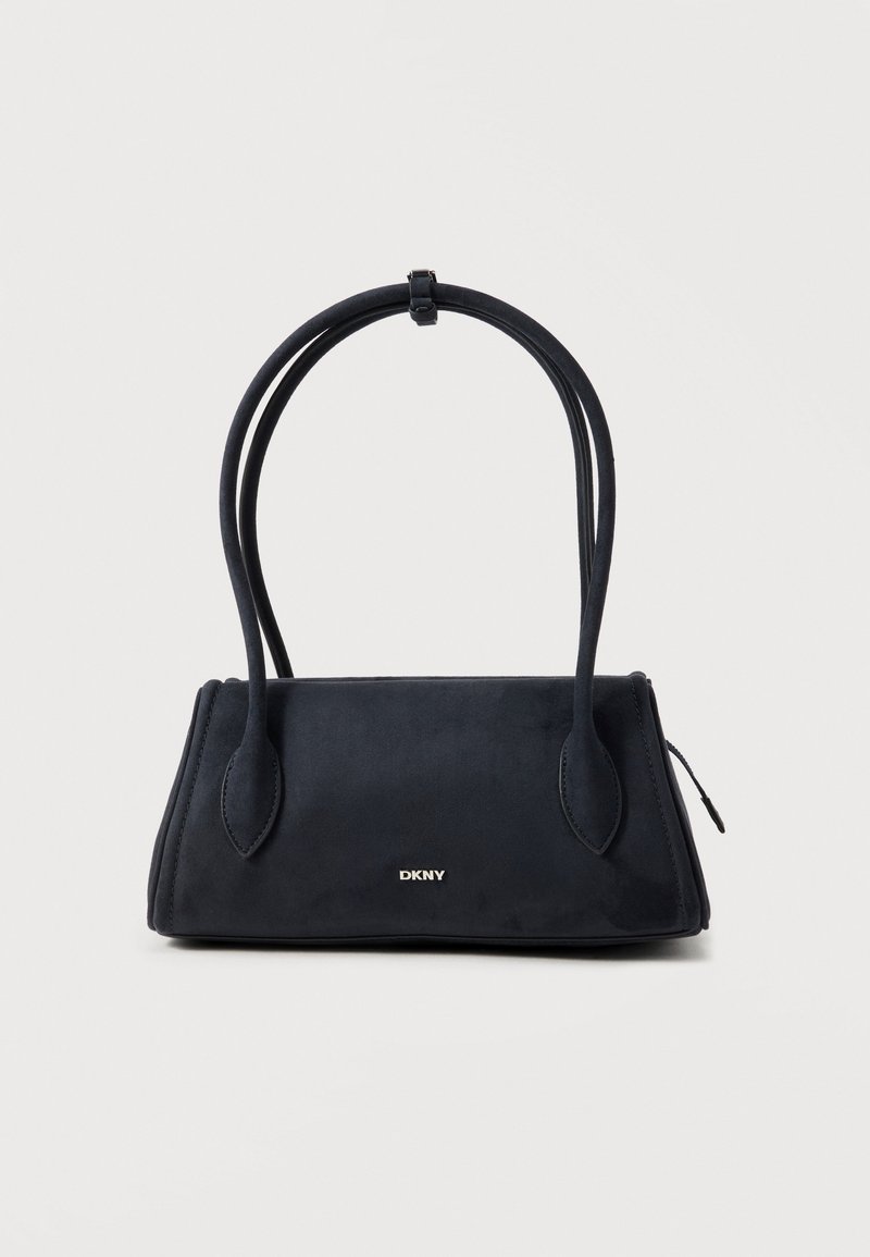 Sac à main noir DKNY avec double anses arrondies et un petit logo métallique sur le devant, sur un fond clair uni.