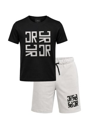 Maglietta nera a maniche corte con grande stampa geometrica astratta bianca, abbinata a pantaloncini grigio chiaro con coulisse e una stampa più piccola abbinate.