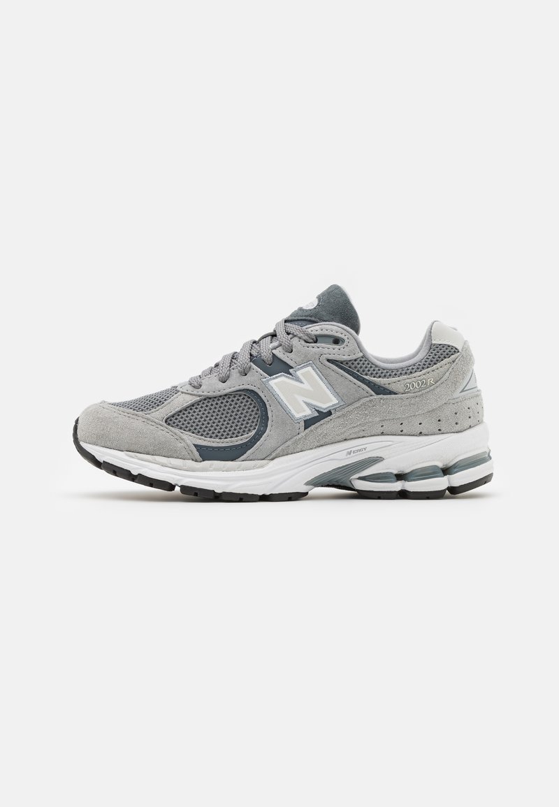 Sneaker grigia realizzata in materiali mesh e suede, con logo bianco, colletto imbottito e suola in gomma texturizzata. Accenti in grigio più scuro.