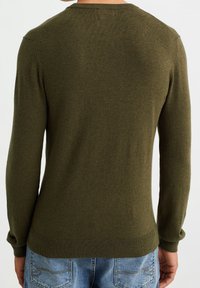 Olivově zelený svetr s kulatým výstřihem, dlouhými rukávy a pružnými manžetami. Materiál vypadá jemně a má lehkou texturu, navržený pro těsný střih.
