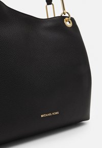 Black leather handbag with textured surface, gold hardware, and embossed logo. Features a spacious hobo shape and a single shoulder strap.