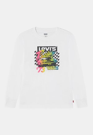 Chemise blanche à manches longues avec un texte coloré "Levi's Racing California Nationals '73" et une voiture vintage sur un fond de drapeau à damier noir et blanc.