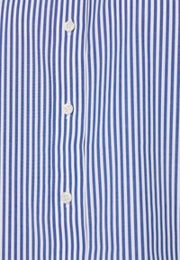 Blå och vit randig tyg med vertikala linjer, med fyra vita knappar arrangerade i mitten. Mjuk textur.