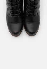Stivaletti neri in pelle con finitura testurizzata, punta rotonda e design con lacci. Presentano cuciture a contrasto e un tacco leggero.