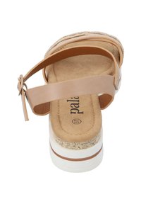 Sandale beige avec une large sangle et une boucle réglable autour de la cheville. Plateforme texturée en liège et semelle intérieure douce et rembourrée. Semelle extérieure en caoutchouc blanc.