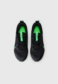 Černé sportovní boty se zelenými akcenty; horní část z prodyšné síťoviny, šněrování, polstrovaný límec a bílá podrážka. Logo Nike na stranách a na jazyku.
