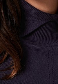 Fioletowy sweter z golfem wykonany z dzianiny, z prążkowaną strukturą i złożonym kołnierzem, o miękkim i gładkim materiale oraz widocznymi detalami szwów.