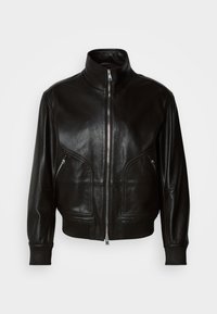 Giacca di pelle nera con colletto alto, chiusura frontale con zip e due tasche con zip, caratterizzata da polsini e orlo a coste. Texture morbida.