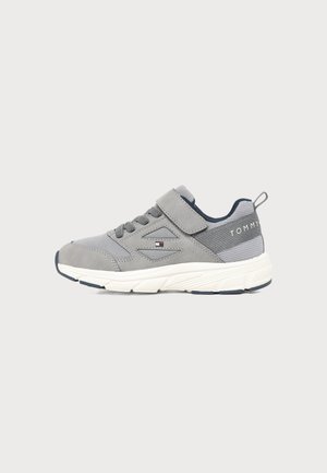 Szary sneaker z białą podeszwą, sznurowadłami i paskiem na rzep, siateczkowym tyłem oraz logo Tommy po boku i z tyłu.