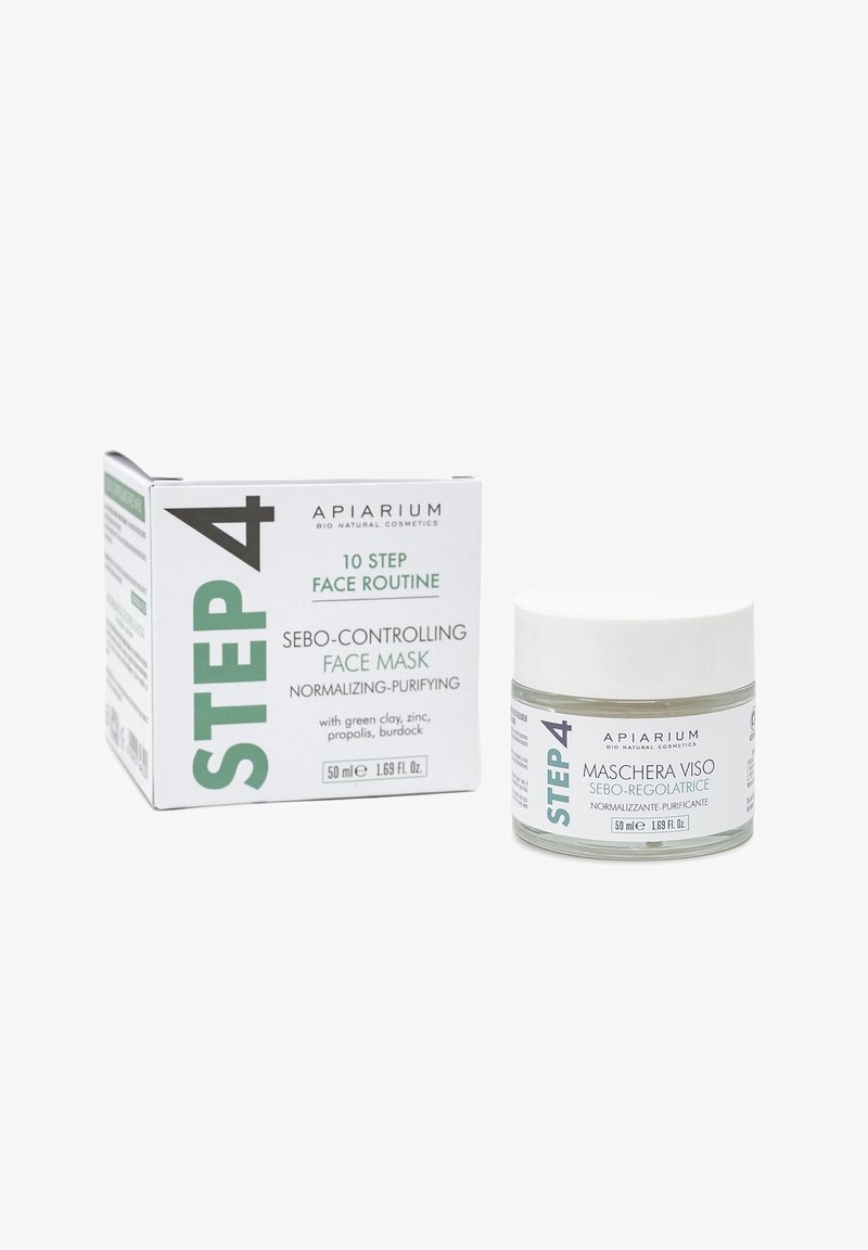 Maschera per il viso controllante il sebo in un barattolo di vetro trasparente con coperchio silver, circondata da una scatola di cartone bianca e verde con testo dettagliato.