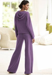 Lila Kapuzenpullover und weite Hose im Set, aus weichem Stoff gefertigt. Verfügt über einen lockeren Schnitt und eine glatte Textur, geeignet für die Freizeit.