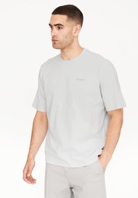 Lys grå t-shirt med korte ærmer, rund halsudskæring og blød tekstur. Har et lille, tonalt logo på brystet og en afslappet pasform.