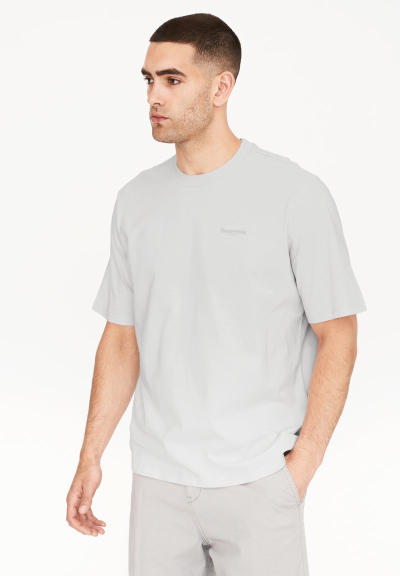 Lys grå t-shirt med korte ærmer, rund halsudskæring og blød tekstur. Har et lille, tonalt logo på brystet og en afslappet pasform.