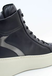 Baskets montantes en cuir noir à finition lisse, avec des accents argentés, semelle en caoutchouc et lacets noirs.