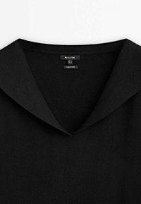 Pull noir à col en V avec un col large, affichant l'étiquette de la marque et les étiquettes de taille à l'intérieur de l'encolure.