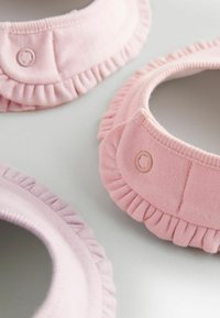 Set of three fabric collars in varying shades of pink, featuring ruffled edges and small button accents. Smooth texture and rounded shape.