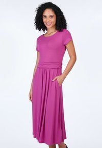 Rosa, knielanges Kleid aus weichem Stoff mit kurzen Ärmeln, tailliertem Bund und Taschen, das einen fließenden, weiten Rock hat.