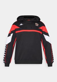 Črna jopa s rdečimi in belimi geometrijskimi poudarki. Ima sprednji žep, kapuco z vrvico in logo Kappa na prsih ter na rokavih.