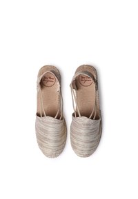 Beige espadrilles dengan bagian atas kain bertekstur, sol jute yang dianyam, dan tali elastis. Memiliki ujung bulat dan pelapis cokelat.