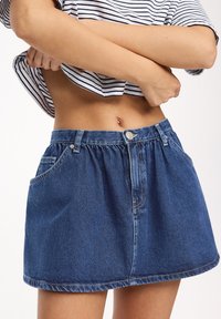 Jeanskjol i mörkblått med lös passform, elastisk midja och framfickor. Nederkanten är avslutad med en subtil kontrasterande söm.