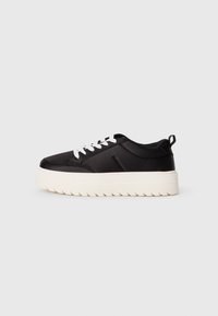 Sneaker nera realizzata in tessuto liscio con suola testurizzata, dotata di lacci bianchi, un dettaglio con logo e una suola alta.