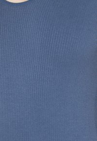 Niebieska bluzka z ryżowym splotem i okrągłym dekoltem, wykonana z miękkiego materiału. Posiada strukturalny wzór i dopasowany krój.