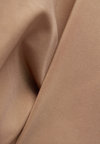 Světlohnědá tkanina s jemnou texturou, která má hladký, matný povrch a jemný vzor žebrování, což vytváří měkký a flexibilní vzhled.