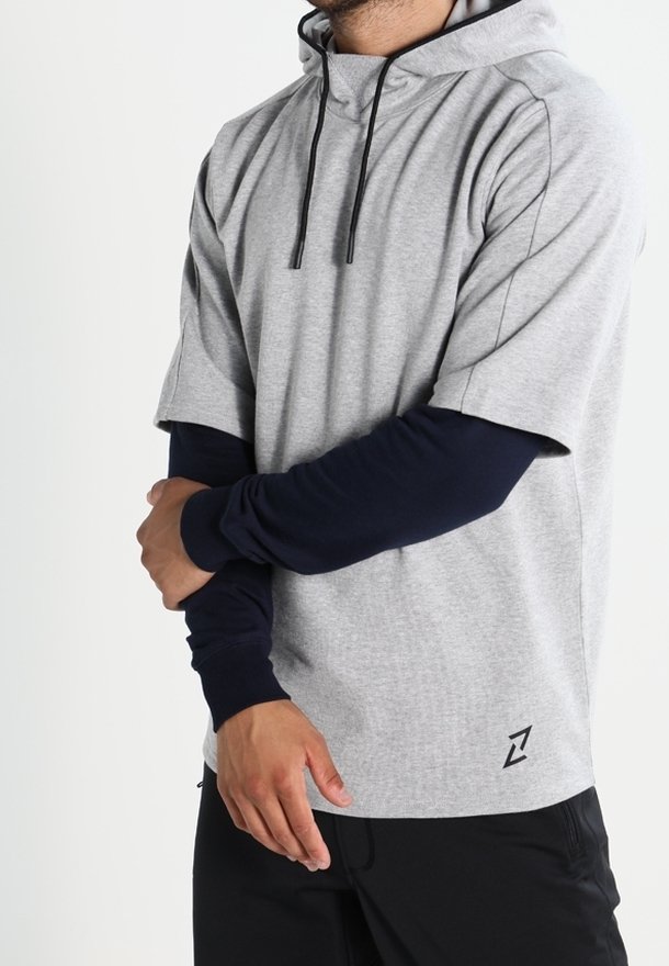 Sudadera corta de manga corta en gris claro con cordones, que presenta una capa inferior de manga larga en color navy y un detalle del logo en la parte inferior derecha.