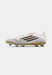 White soccer cleat with black stripes, textured upper, and a subtle gradient pattern. Features a molded outsole with visible studs.