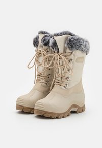 Botas impermeables beige con suelas de goma texturizadas, borde de piel sintética y cordones resistentes. Diseño elevado en el tobillo para mayor estabilidad en climas fríos.