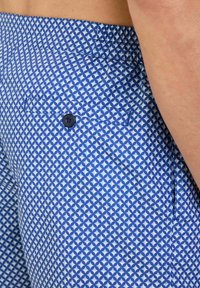 Pantaloni corti blu con un design geometrico. Presentano una tasca posteriore con un bottone nero e una cintura elastica per il massimo comfort.