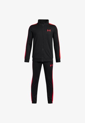 Črn trenirkasti komplet iz gladkega materiala, ki vključuje rdeče stranske črte, jakno z visokim ovratnikom in zip zapenjanjem ter usklajene oprijete hlače z logotipnimi akcenti.
