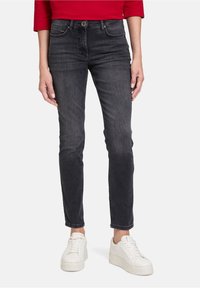 Černé džíny z denimu v slim fit, vyrobené z měkké tkaniny, s pěti kapsami a minimálním vyblednutím, doplněné bílými teniskami.