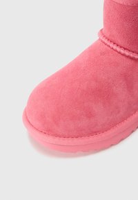 Bottine en daim rose avec un bout arrondi, texture douce et semelle en caoutchouc assortie avec des détails de couture visibles.