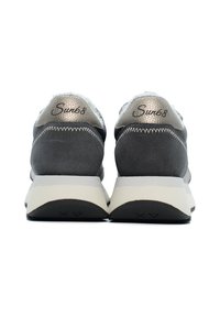 Scarpe da ginnastica grigie e argentate con una tomaia testurizzata, una suola intermedia bianca a contrasto e un marchio ben visibile sul tallone. Forma arrotondata, design ammortizzato.