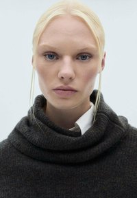 Ciemnoszary sweter dziany z wysokim, złożonym kołnierzem, nałożony na białą koszulę, charakteryzujący się gładką fakturą i minimalistycznym designem.
