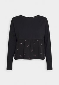 Svart långärmad topp med en rynkad, texturerad nederdel som har små, lila paisleymönster. Rund halsringning, avslappnad passform.