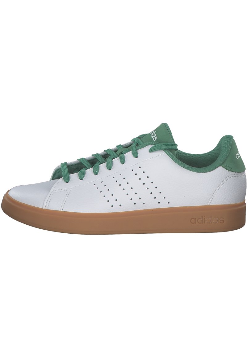 Zapatilla blanca con acentos verdes, hecha de cuero suave, con perforaciones en el costado y una suela de goma marrón. Cintas en color verde a juego.