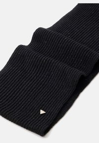 Sciarpa nera a coste realizzata in tessuto morbido, con una leggera lucentezza. Include un piccolo accent metallic triangolare vicino al bordo.