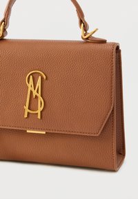 Bruine leren handtas met een gestructureerd oppervlak, voorzien van een gouden logo en sluiting. Het heeft een strak gevormde structuur en een korte handgreep.