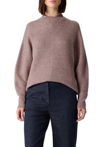 Jasnofioletowy dzianinowy sweter o prążkowanej fakturze, z wysokim kołnierzem i opuszczonymi ramionami. Połączony z ciemnoniebieskimi, dopasowanymi spodniami.