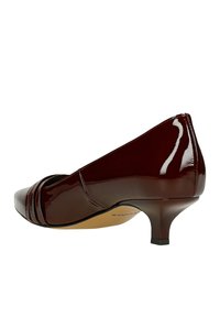 Décolleté in pelle lucida bordeaux con punta affusolata, caratterizzata da dettagli plissettati e un modestissimo tacco a stiletto. Texture liscia e lucente.