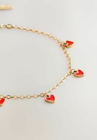 Gold chain bracelet featuring small red enamel heart charms, evenly spaced along the chain, with a simple clasp closure.
