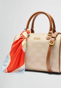 Borsa beige con finitura testurizzata, dettagli in pelle marrone e una sciarpa di seta colorata legata al manico. Presenta un dettaglio del logo.