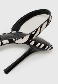 Black high-heeled sandals with a narrow, pointed sole. The straps feature a black and white animal print with a soft texture.