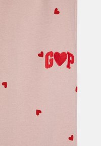 Rožinė medžiaga su mažais raudonais širdelėmis ir siuvinėtu "G♥P" logotipu, su lygiu paviršiumi ir tankia struktūra.