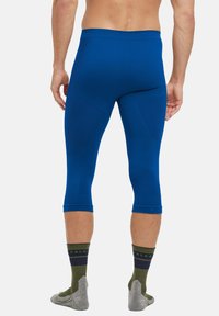Blue form-fitting capri-length leggings made of stretchy material, featuring textured panels and a smooth waistband, paired with gray-green socks.