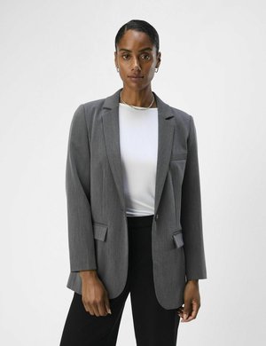Blazer grigio su misura con rever a notched, chiusura a un bottone e due tasche frontali. Abbinato a una maglietta bianca e pantaloni neri.