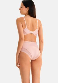 Ensemble lingerie rose clair comprenant un soutien-gorge en tissu lisse avec des accents en dentelle et une culotte taille haute bordée d'un motif floral, avec des bretelles réglables.