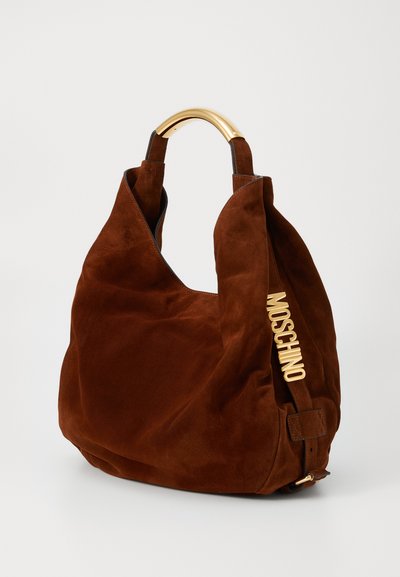 Brun mocka hobo-väska med ett handtag i guldmetall och en sidodetalj med ordet "MOSCHINO." Mjuk textur och överdimensionerad design.